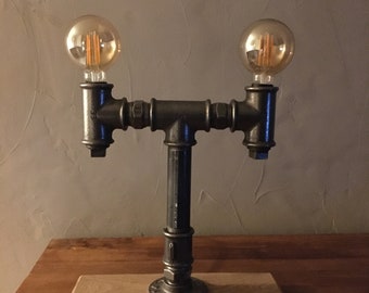 lampe à poser réalisé a partir de coudes de plomberie en fonte le tout monté sur un socle en chêne massif.