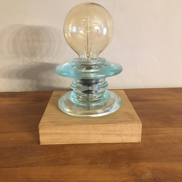 lampe à poser réalisée à partir d'un ancien isolateur électrique en verre des années 40 le tout monté sur un socle en chêne massif.