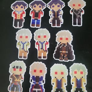 May include: A collection of ten pixel art figures crafted from small plastic beads. Each figure depicts a stylised character with distinct hair colours, including dark blue, silver, and light green, and various outfits in red, blue, black, and yellow.