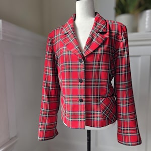 Puede incluir: Una chaqueta de cuadros roja y negra con un cierre de botón único y un bolsillo en el lado izquierdo.