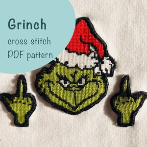 Op de afbeelding: Kruissteekpatroon voor de Grinch, met een groene Grinch met een rode kerstmanmuts en twee middelvingers. Het patroon is gelabeld "Grinch cross stitch PDF pattern".