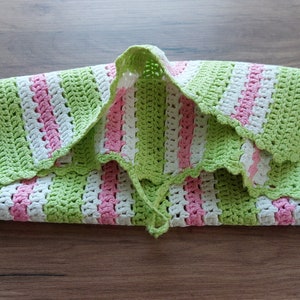 Può includere: Una copertina per neonati a righe verdi e rosa in crochet con un bordo a festoni.