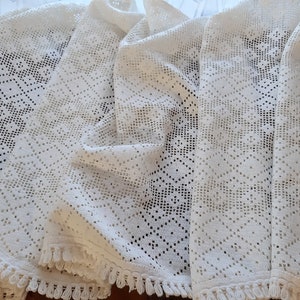 May include: Four white crocheted tablecloths with a diamond pattern and fringe trim.