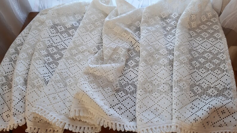 May include: Four white crocheted tablecloths with a diamond pattern and fringe trim.