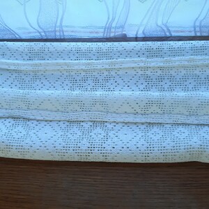 May include: White crocheted curtain panel with a diamond pattern and a fringed edge.