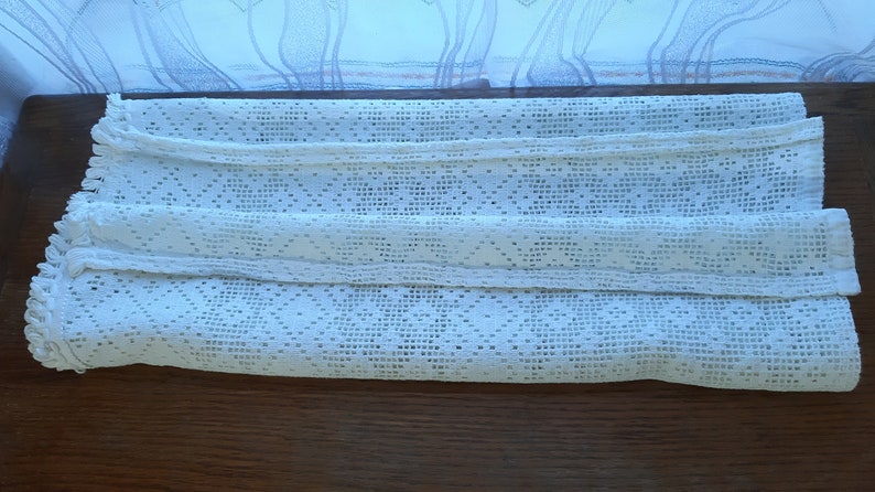 May include: White crocheted curtain panel with a diamond pattern and a fringed edge.