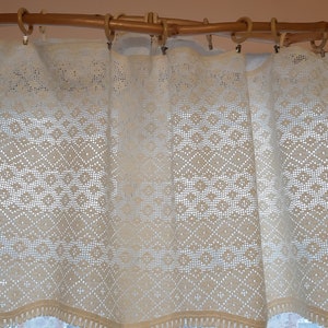 May include: White crocheted valance with a diamond pattern, hanging on a wooden rod.