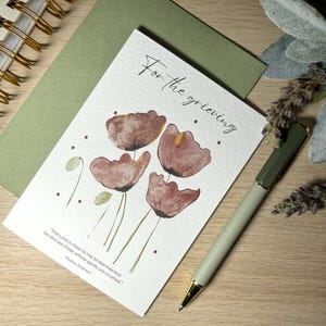 May include: A sympathy card featuring watercolour flowers and the words "For the grieving." A green envelope and a green and gold pen are also present. The card includes a Bible verse.