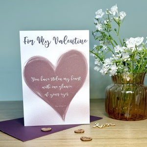 May include: Valentine's card featuring a mauve heart design with the text "For My Valentine". The card includes a romantic quote inside the heart. A purple envelope and wooden heart decorations are also present.