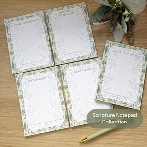 May include: Four rectangular paper notepads with lined pages and a green botanical leaf border. The pads are titled Count Your Blessings, Bible Verses To Remember, Prayer Requests, and Today's Notes. A light green pen rests near the bottom right.