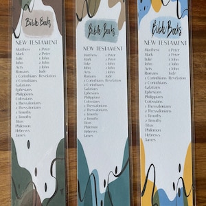 May include: Three bookmarks with a colourful abstract design and the text "Bible Books" and "New Testament" with a list of the books of the New Testament.