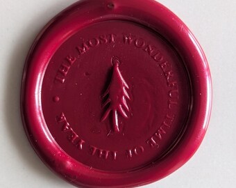 May include: A red wax seal with the text "The Most Wonderful Time of the Year" and a stylized pine tree design.