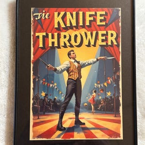 May include: Framed vintage circus poster titled "The Knife Thrower." The artwork depicts a man in a vest and boots, holding knives, with a woman in a red dress in the background. The poster has a red, yellow, and blue color scheme.