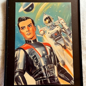 May include: Framed vintage science fiction art print featuring a man in a futuristic suit with a robot in space. The artwork has a retro style with a blue and orange color scheme, and a planet in the background.