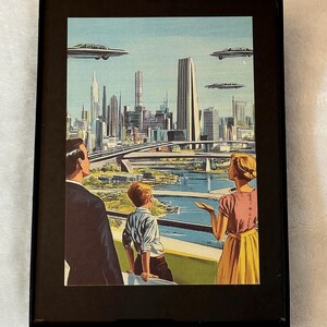 May include: Framed vintage print depicting a futuristic cityscape with flying cars. The artwork features a family looking out over the city, with a blue sky and a river. The print is in a black frame.
