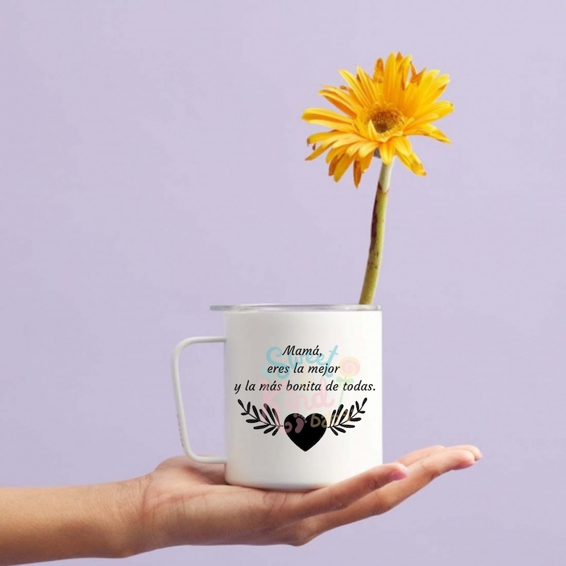 May include: White ceramic mug with a black handle and a floral design. The mug has the text "Mam&aacute;, eres la mejor y la m&aacute;s bonita de todas." with a heart in the center.
