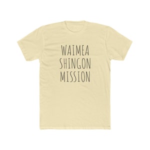 May include: A light beige t-shirt with the text "Waimea Shingon Mission" printed in black.