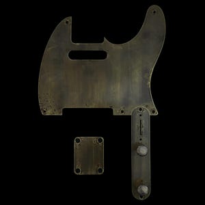 Peut inclure: Un ensemble de pièces de guitare de style vintage, comprenant un pickguard, une plaque de contrôle et une plaque de manche, toutes avec une finition en laiton terni. Le pickguard a une forme unique avec une découpe pour les micros et une ouverture rectangulaire.