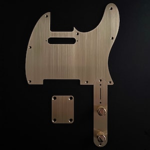 以下が含まれることがあります： ブラシ仕上げの金色の金属製ギターピックガード。ピックガードは、丸みを帯びた角とピックアップ用の切り抜きのある長方形です。ピックガードには、2つのノブが付いたコントロールプレートもあります。