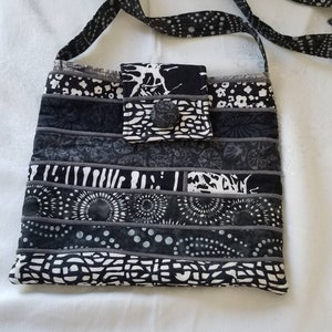 May include: Black and white patchwork crossbody bag with a flap closure and a button. The bag has a long adjustable strap.