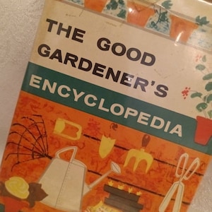 May include: The Good Gardener's Encyclopedia book cover with an orange background and illustrations of gardening tools, a watering can, a seed packet, and a book. The text on the cover reads "The Good Gardener's Encyclopedia month by month in the garden."