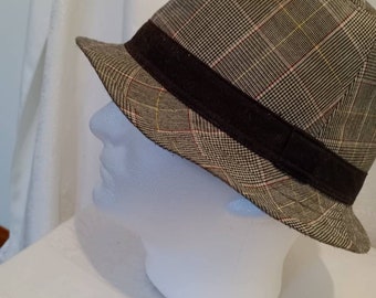 May include: A brown and gray plaid fedora hat with a black band.