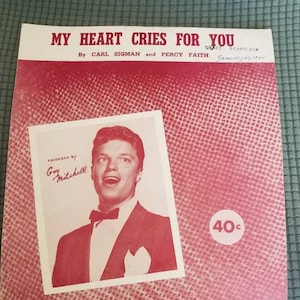 May include: A vintage sheet music cover for the song "My Heart Cries For You" by Carl Sigman and Percy Faith. The cover features a black and white photo of a man in a suit singing, with the text "Recorded by Guy Mitchell" and "40c" printed on the cover.