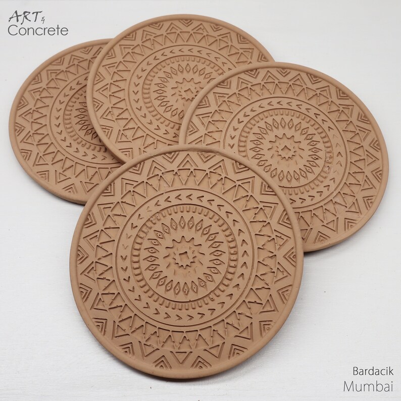 Puede incluir: Conjunto de cuatro posavasos de hormig&oacute;n marr&oacute;n con un patr&oacute;n geom&eacute;trico. Los posavasos presentan un dise&ntilde;o circular con c&iacute;rculos conc&eacute;ntricos y tri&aacute;ngulos.