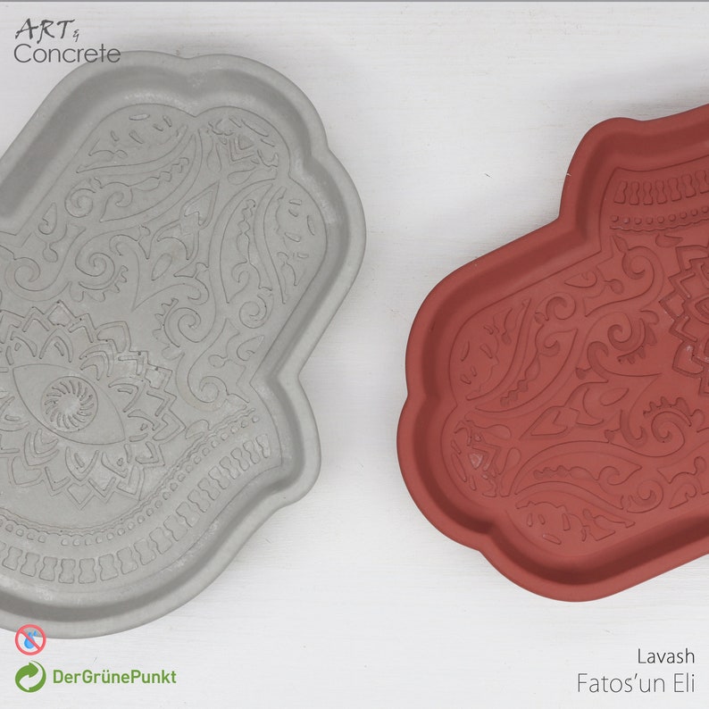 May include: Two decorative concrete trays in the shape of a hamsa hand. The tray on the left is gray and the tray on the right is red. Both trays have an intricate design with a central eye.