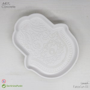 May include: White ceramic tray shaped like a hamsa hand with an intricate floral design. The tray is a decorative piece for home decor.