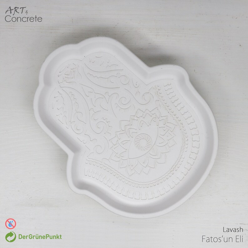 May include: White ceramic tray shaped like a hamsa hand with an intricate floral design. The tray is a decorative piece for home decor.
