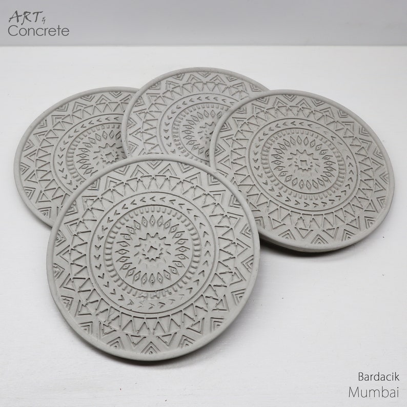 Puede incluir: Conjunto de cuatro posavasos de hormig&oacute;n gris con un patr&oacute;n geom&eacute;trico. Los posavasos son redondos y tienen un dise&ntilde;o en relieve.