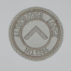 May include: A silver embroidered patch with the words "Aldborough Lodge No. 538" in a circle around a silver chevron.