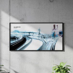 Puede incluir: Una impresión artística enmarcada con un diseño de paisaje abstracto en tonos azules, negros y blancos. La impresión presenta carreteras y estructuras, con el texto "OK COMPUTER" visible. La obra se exhibe en una pared de hormigón.