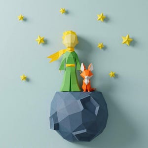 May include: A papercraft scene featuring a green-clad figure with a yellow scarf and hair, standing with an orange fox on a blue planet. Yellow stars are scattered against a light blue background. The figures are made of folded paper.
