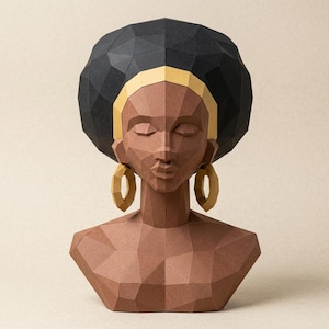 May include: A geometric paper sculpture of a woman's bust. The sculpture features a black afro, gold headband and earrings, and a brown face and torso. The artwork is made of folded paper.
