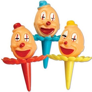 May include: Three colorful clown cake toppers with smiling faces, red, yellow, and blue. Each topper has a ruffled base and a clown face with a red nose and closed eyes.