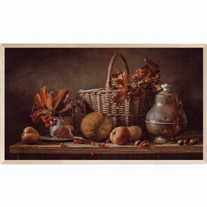 Puede incluir: Naturaleza muerta con una cesta de mimbre, una olla de cobre y frutos otoñales. La composición incluye una pequeña calabaza, manzanas y bayas rojas, dispuestas sobre una superficie de madera. La imagen está enmarcada en madera clara.