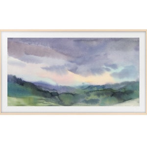 May include: Watercolor landscape painting featuring a serene mountain scene under a cloudy sky. The artwork showcases shades of green, blue, and purple, framed in a light wood frame. The painting evokes a sense of tranquility.