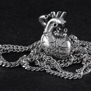 Op de afbeelding: Een zilveren anatomisch hart hanger ketting met een gedetailleerd ontwerp. Het hart is bevestigd aan een zilveren curb chain.
