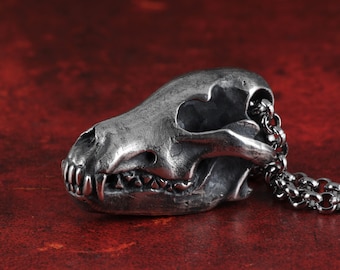May include: A silver metal pendant in the shape of a wolf skull with a silver chain.
