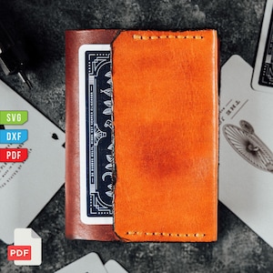 May include: A handmade leather card wallet in a rich orange hue, with a contrasting brown interior. The wallet is stitched with a light-colored thread and holds a blue playing card. The design is minimalist and features a classic, durable construction.