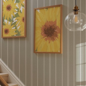 May include: Two framed sunflower paintings in yellow and brown tones adorn a striped wall. A clear glass pendant light with a brass fitting hangs from the ceiling. A wooden staircase with a light-coloured banister is in the foreground.