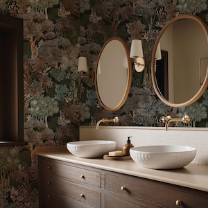 May include: A bathroom scene featuring two oval mirrors with wooden frames, mounted above white vessel sinks. The sinks sit on a dark wood vanity with brass fixtures. The wallpaper has a forest design in shades of green, brown, and black.