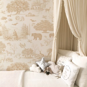 May include: A cozy nursery scene featuring a cream-colored canopy bed with decorative pillows and a white waffle-knit blanket. The wallpaper has a beige forest scene design. Plush toys include a star, cloud, and heart-shaped pillow.