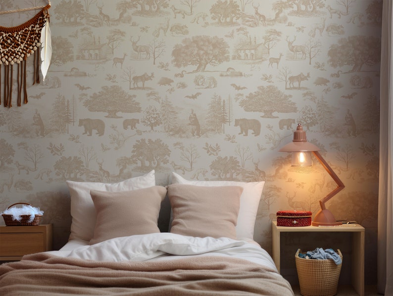 May include: A bedroom scene featuring a bed with white linens and tan pillows, complemented by a matching throw. The wall is adorned with wallpaper depicting a forest scene with bears, deer, and trees. A pink lamp and a woven basket add decorative touches.