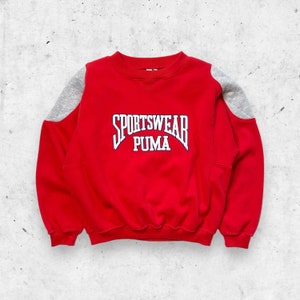 Puede incluir: Sudadera roja con paneles de hombros grises y un logotipo "Sportswear Puma" azul y blanco.