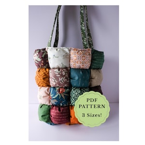 May include: A patchwork tote bag with a grid-like design, featuring various patterned fabric squares in shades of green, orange, brown, and blue. The bag has green straps with a white floral pattern. A green label reads "PDF PATTERN 3 Sizes!"