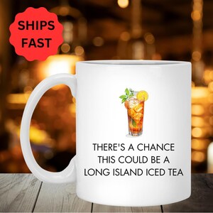 Könnte beinhalten: Eine weiße Keramiktasse mit einer schwarz-weißen Grafik eines Glases Eistee mit einer Zitronenscheibe und einem Minzblatt. Der Text auf der Tasse lautet "There's a chance this could be a Long Island Iced Tea."