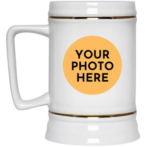 May include: White ceramic beer stein with a gold trim around the top and bottom. The stein has a large, round, orange circle in the center with the text "YOUR PHOTO HERE" in black.